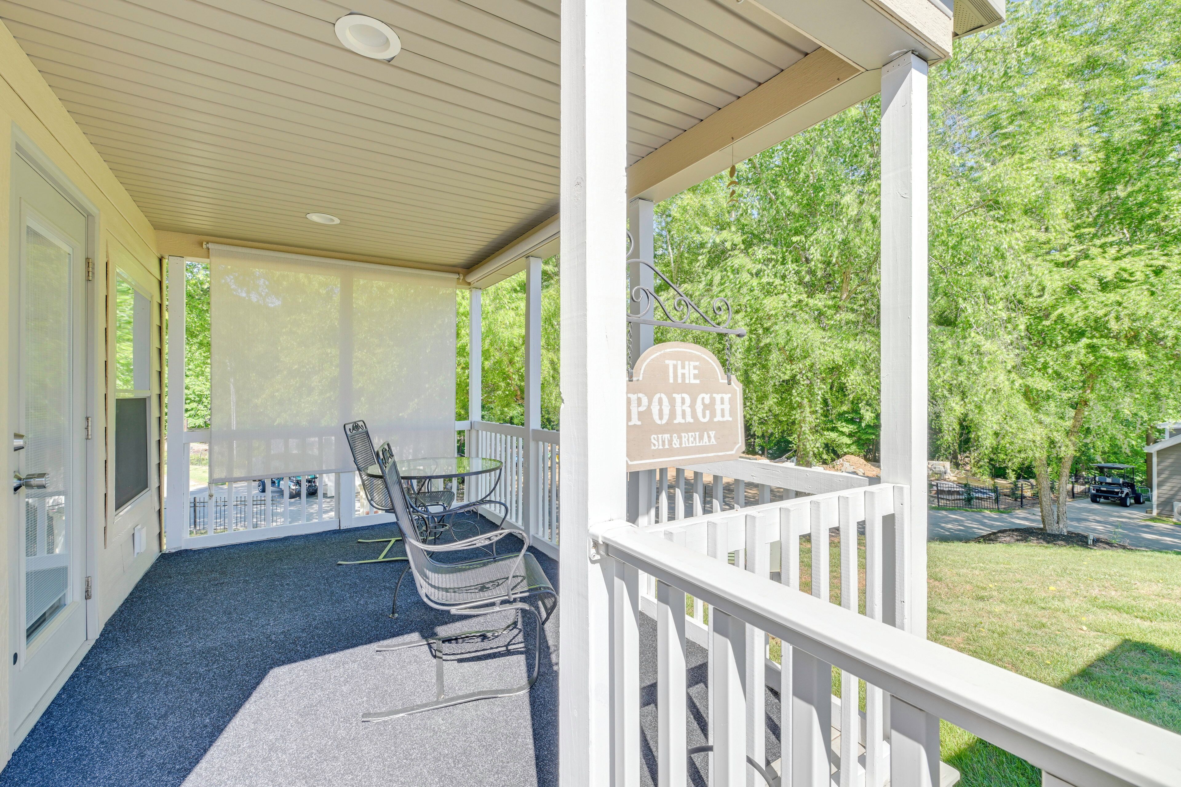 A covered porch with a sign reading 'The Porch Sit & Relax,' a glass table, and two chairs.