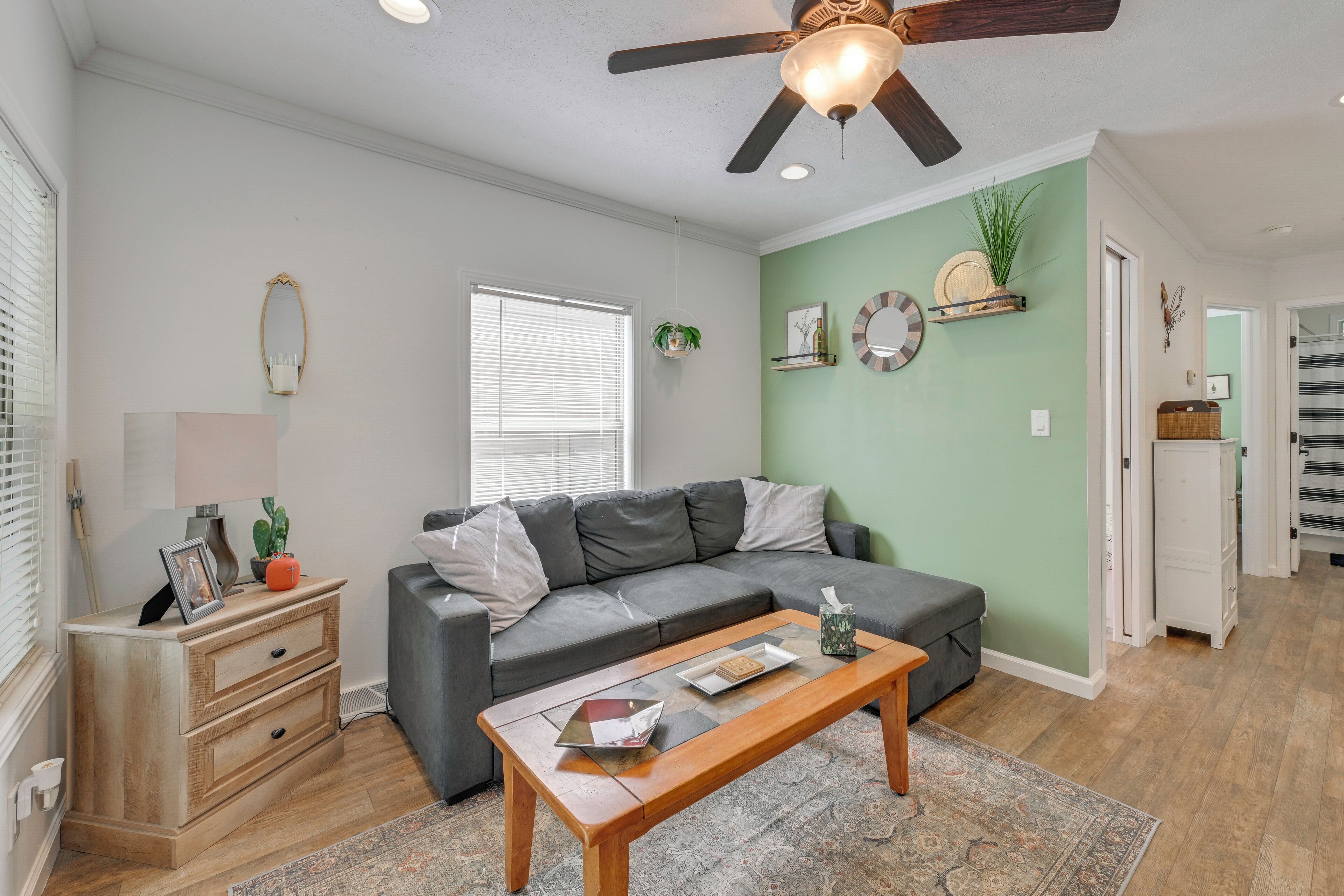 A living room with a grey sofa, wooden coffee table, and a ceiling fan.