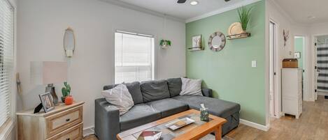 A living room with a grey sofa, wooden coffee table, and a ceiling fan.