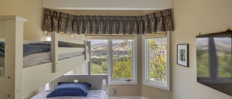 A bedroom with bunk beds, a large window with a view, and a mounted television.