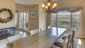 A dining area with a glass table, chairs, a fireplace, a chandelier, and a view of the landscape. - Combined Retreat w/ Epic Views in Simi Valley! (Simi Valley)