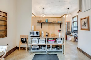 A kitchen with a microwave, coffee maker, and storage containers on shelves.