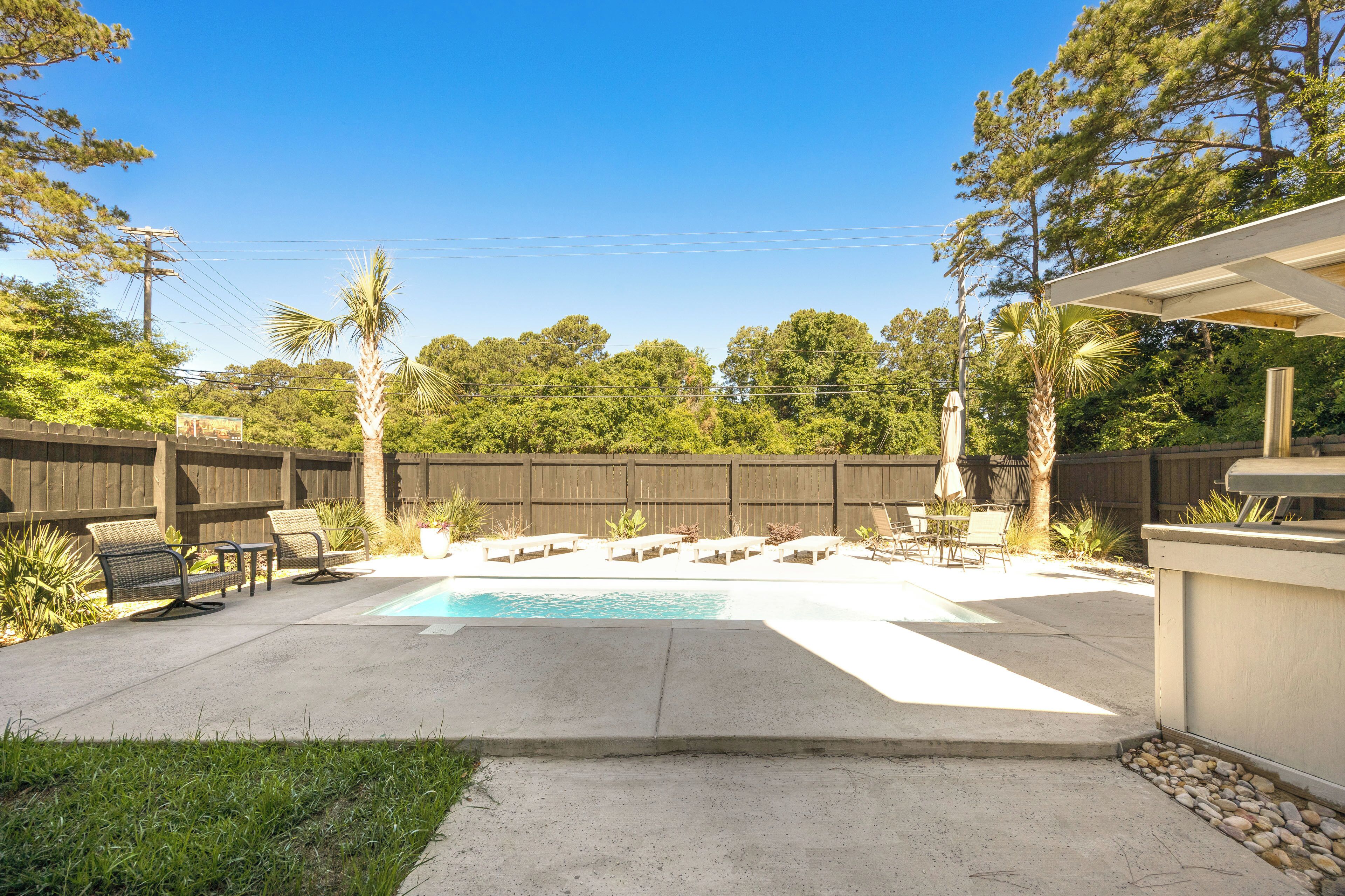A backyard with a swimming pool, outdoor furniture, and a wooden fence.