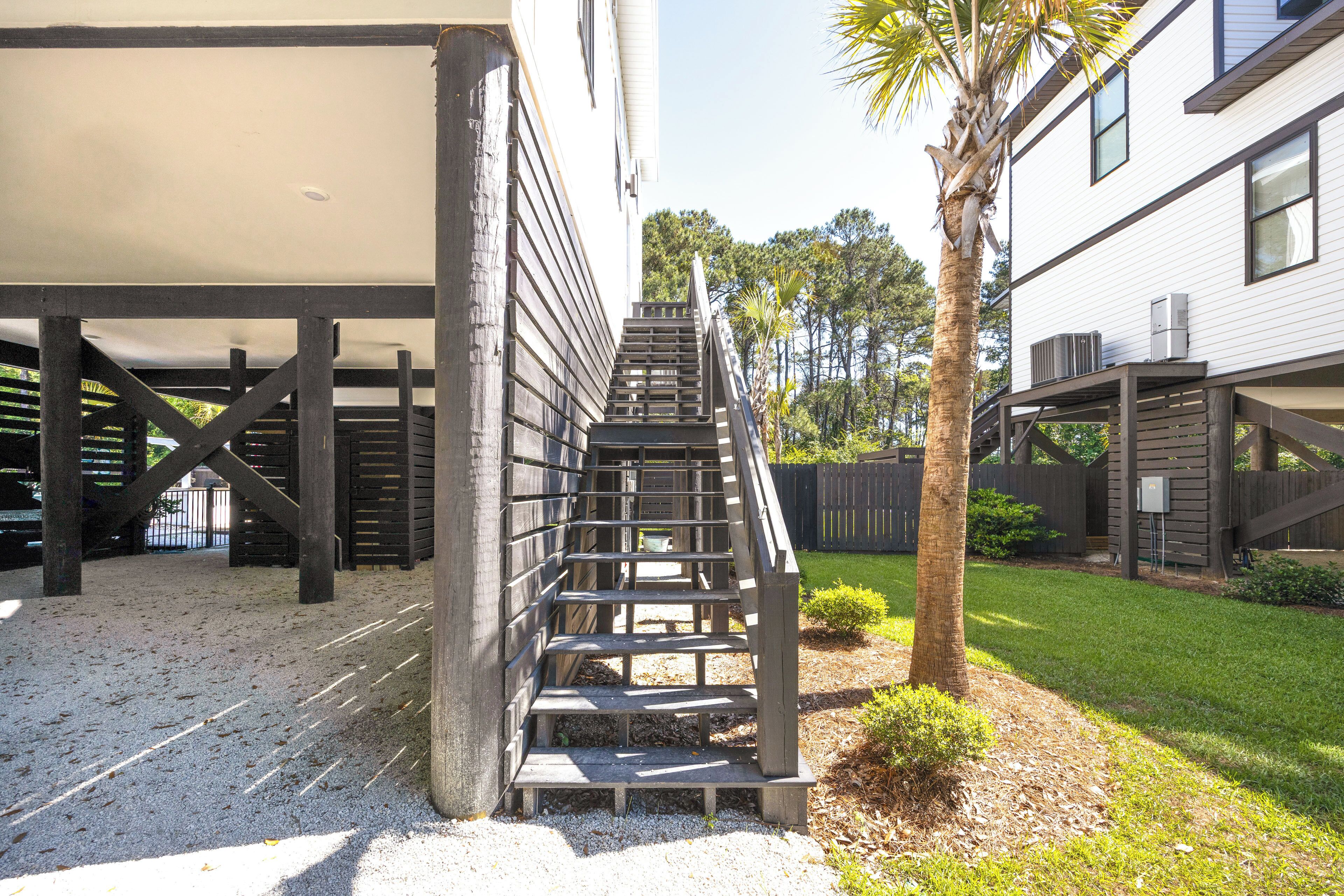 A staircase leading to a covered area, a palm tree, and a building with a white exterior.