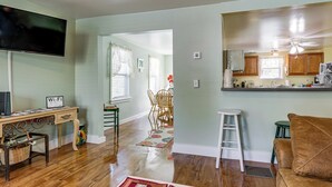 A living room with a TV, wooden flooring, a dining area with chairs, a kitchen with wooden cabinets, and a staircase. - Near Trails! Riverside 2-unit Combo in Franklin (Franklin)