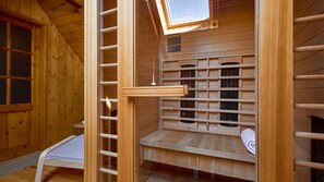 Un sauna avec des murs en bois, un banc, une lucarne et une petite table.