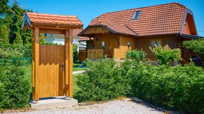 Une maison en bois avec un toit recouvert de tuiles rouges, une porte en bois et un jardin bien entretenu.