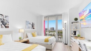 A hotel room with two beds, a balcony with a city view, and a large painting on the wall. - Marina Front - 2BR - Beachwalk Resort (Hallandale Beach)