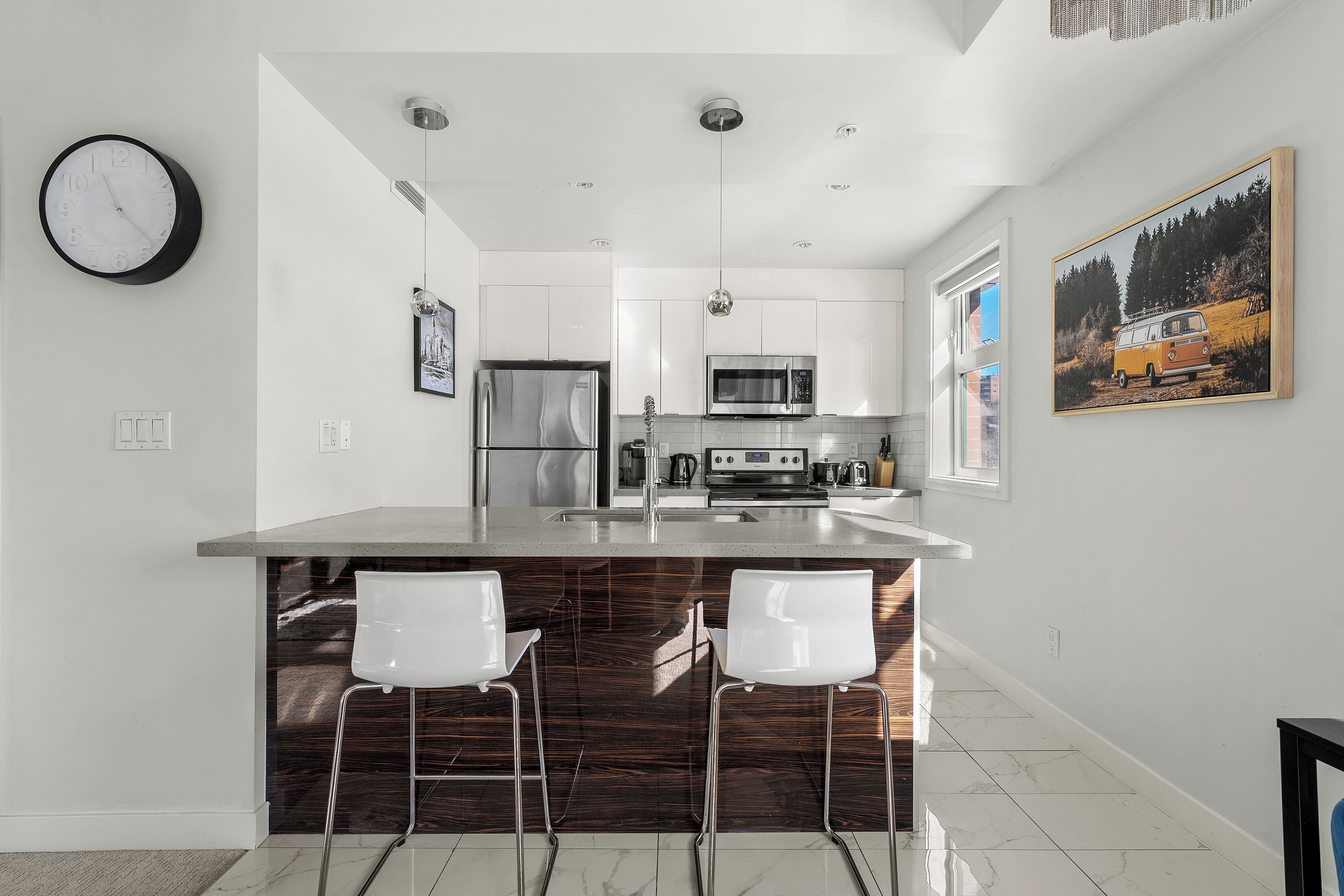 A modern kitchen with a central island, stainless steel appliances, and white cabinetry.