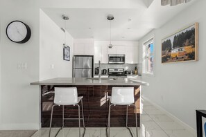 A modern kitchen with a central island, stainless steel appliances, and white cabinetry. - 2 Bed, 2 Bath Condo in the Heart of Downtown Calgary Near Saddledome & Stampede (Calgary)