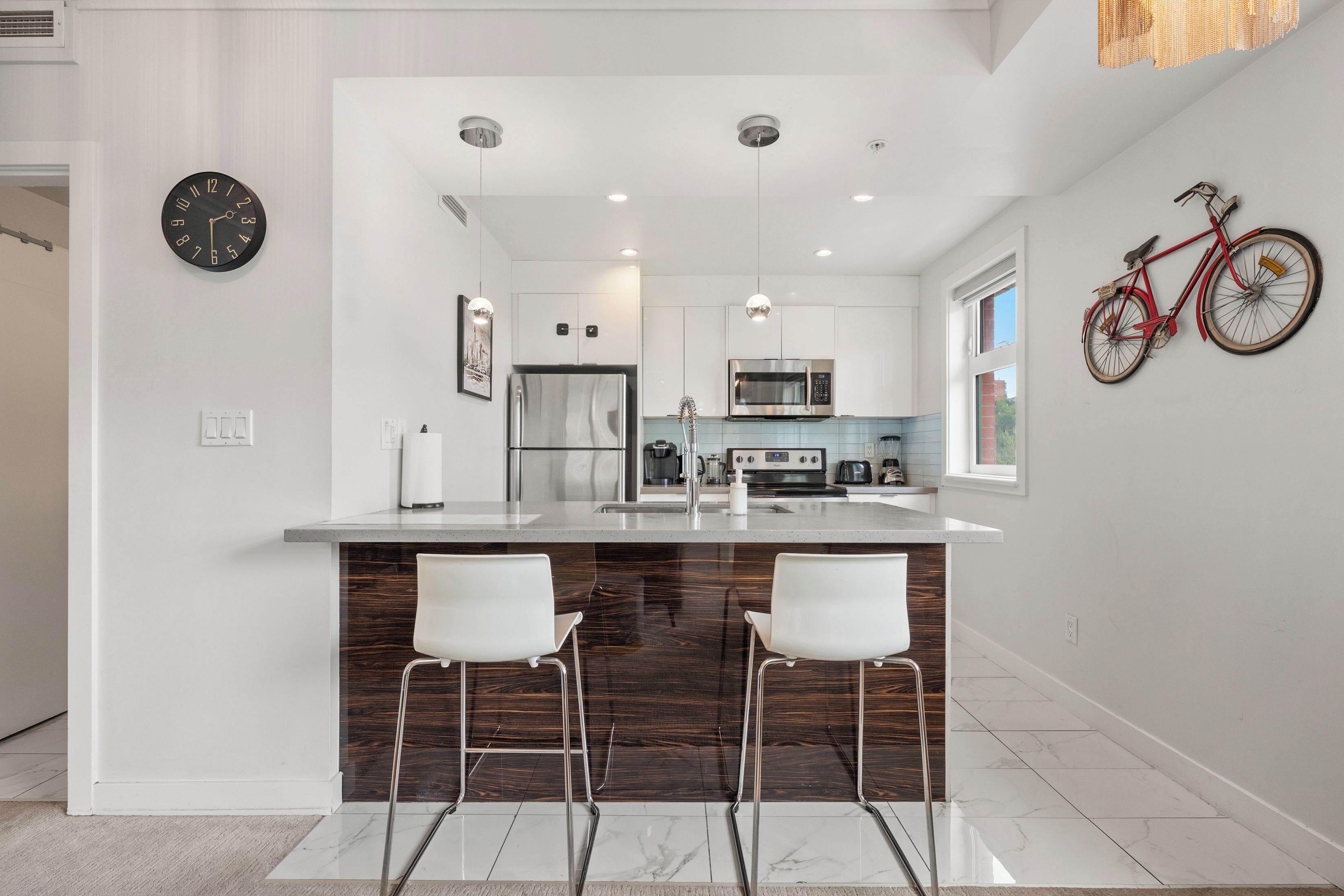 Una cocina moderna con una isla central, electrodomésticos de acero inoxidable y una bicicleta colgada en la pared.
