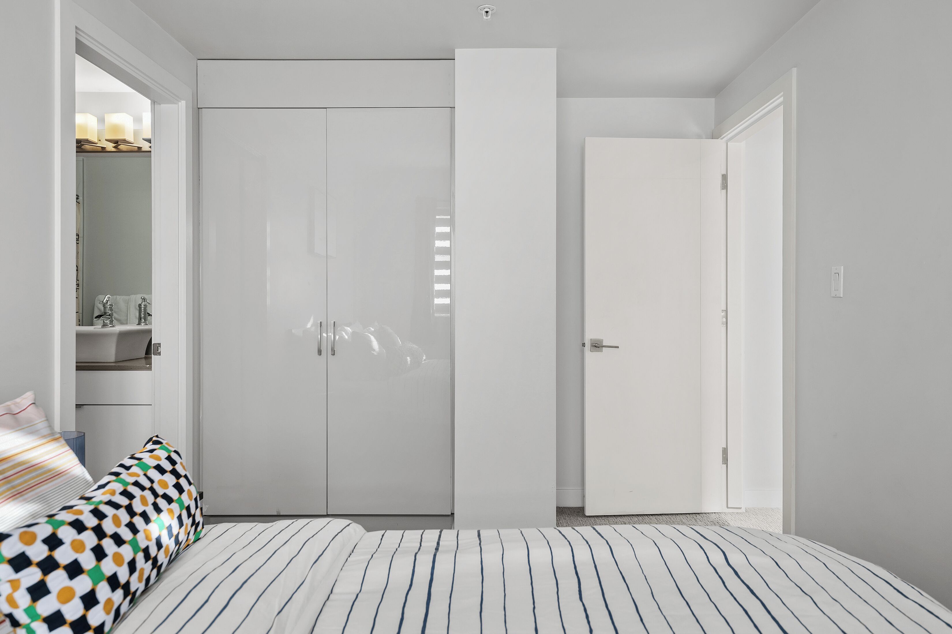 A bedroom with a bed, a wardrobe, and a door leading to another room.