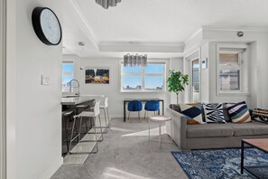 A modern living room with a sofa, chairs, a dining area, and a view of the city. - 2 Bed, 2 Bath Condo in the Heart of Downtown Calgary Near Saddledome & Stampede (Calgary)