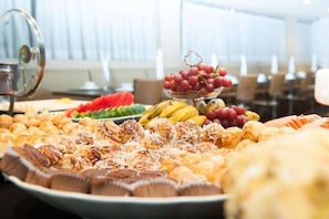 Un buffet proposant une variété de plats, notamment des fruits, des pâtisseries et des chocolats.