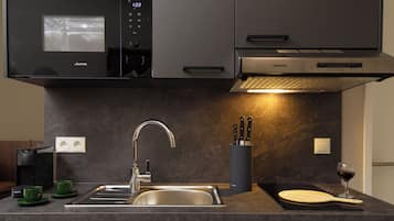 Een moderne keuken met een ingebouwde magnetron, een roestvrijstalen spoelbak en een messenblok.