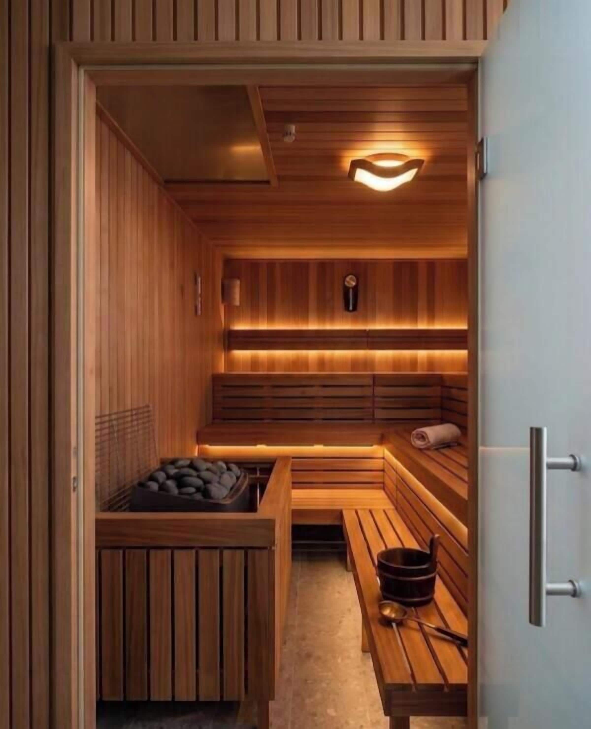 Eine Sauna mit Holzbänken, einer Bank mit Handtuch und Ablage für Steine.