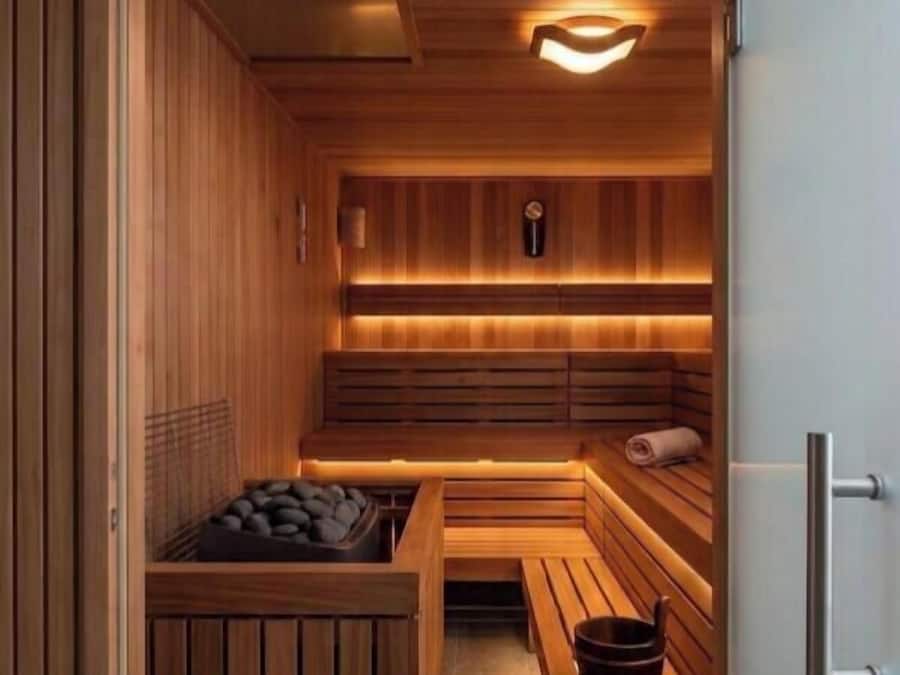 Eine Sauna mit Holzbänken, einer Bank mit Handtuch und Ablage für Steine.