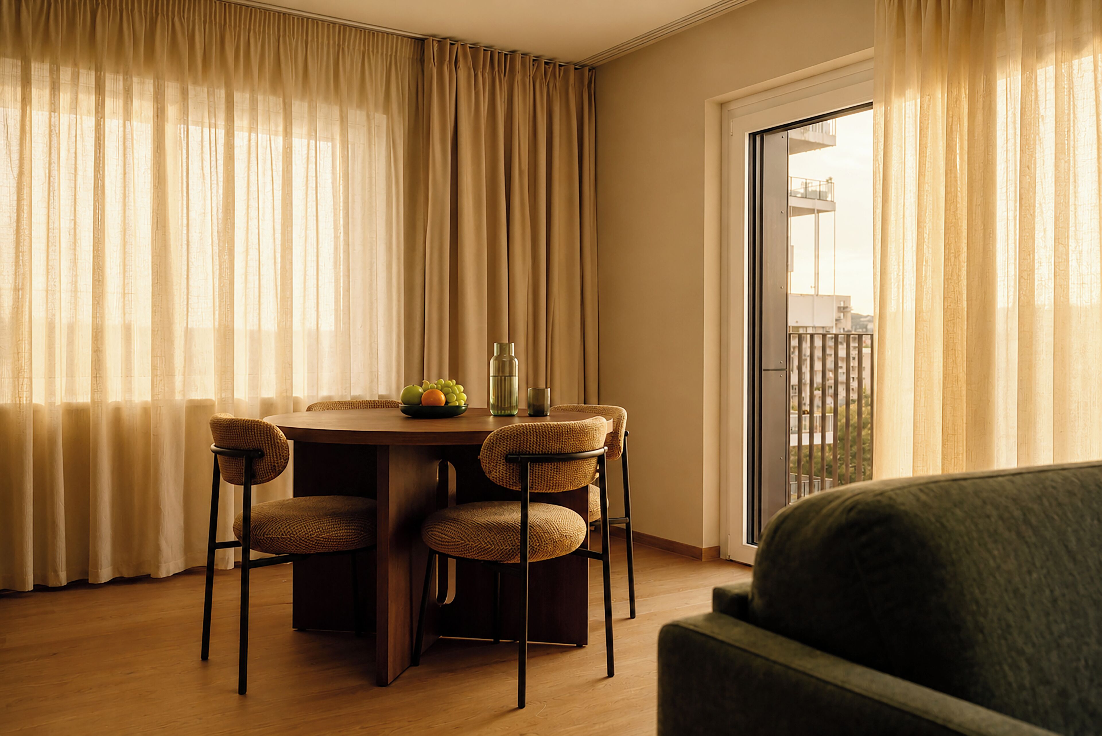 A dining area with a round table, four chairs, a vase, and a fruit bowl.
