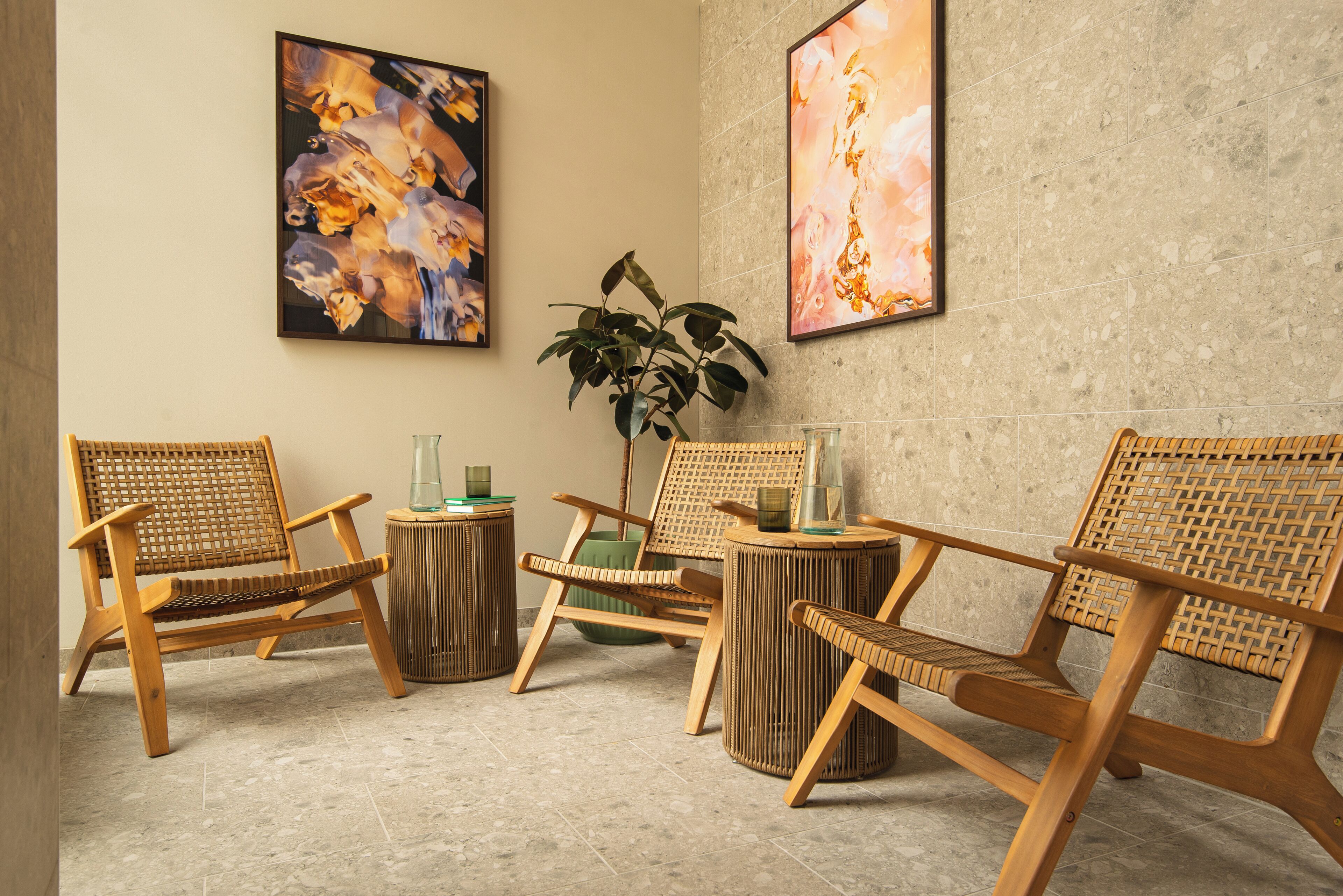 Une pièce avec quatre chaises en bois, une plante verte et deux tableaux abstraits accrochés au mur.