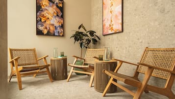 Une pièce avec quatre chaises en bois, une plante verte et deux tableaux abstraits accrochés au mur.