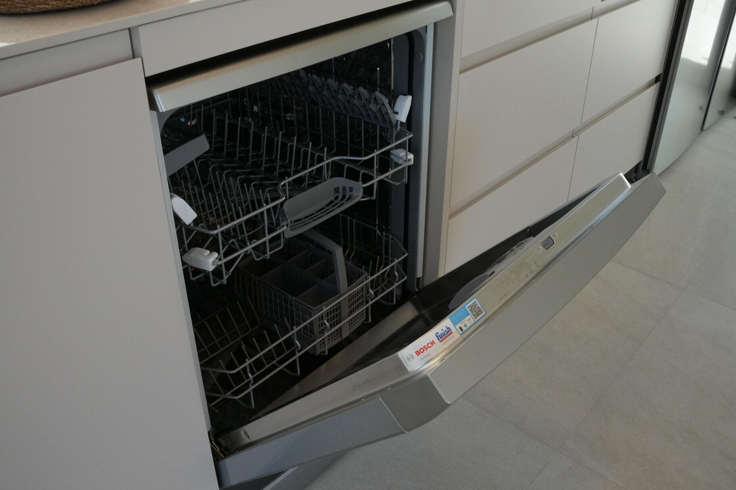 Un lave-vaisselle de marque Bosch, un sol carrelé et un meuble de cuisine.