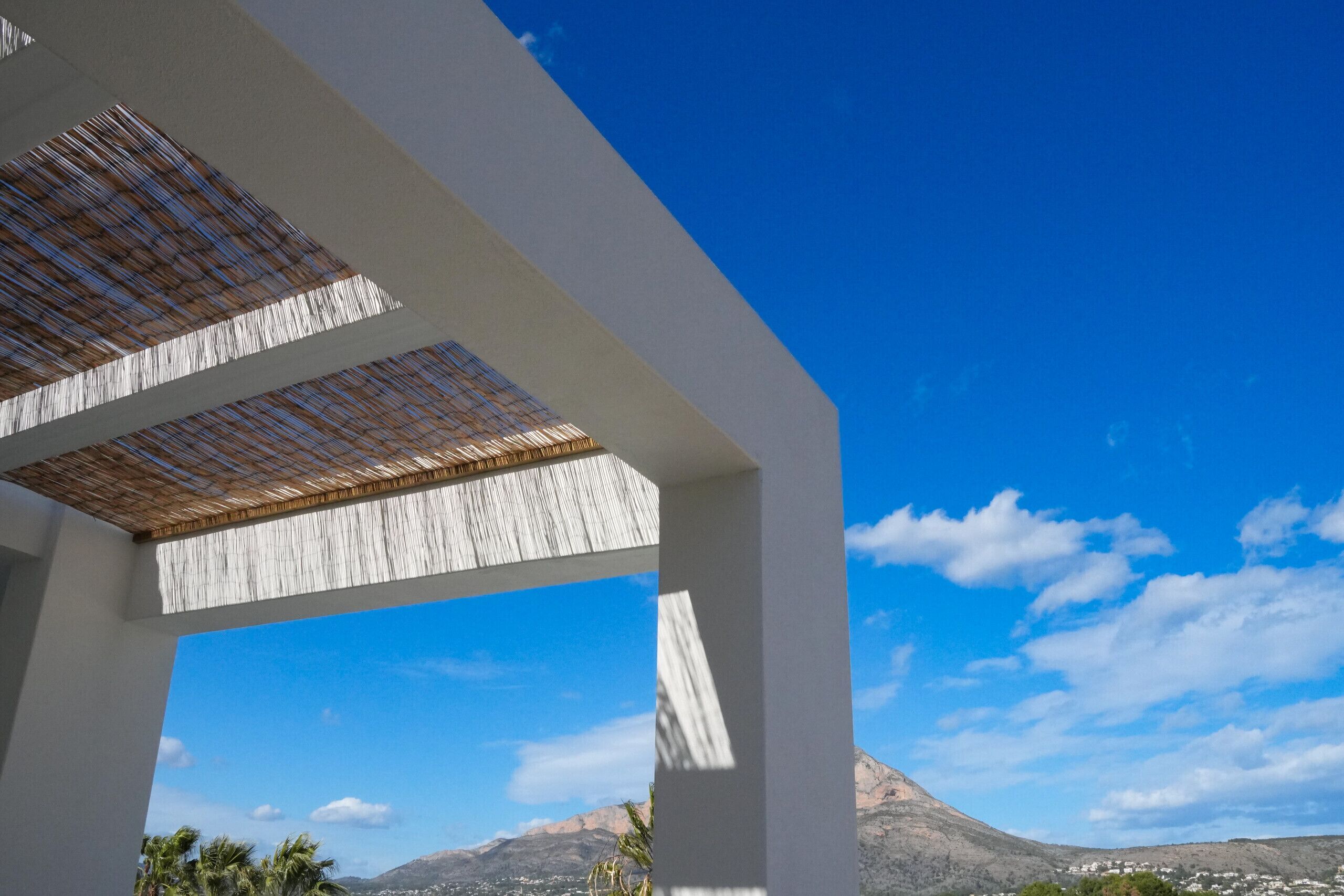 Une structure architecturale moderne offrant une vue dégagée sur une montagne et une ville en arrière-plan.