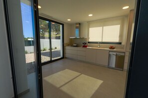 A modern kitchen with a dishwasher, a window, and a sliding door leading to an outdoor area. - 0143 Villa Cap Cabanes (Javea)