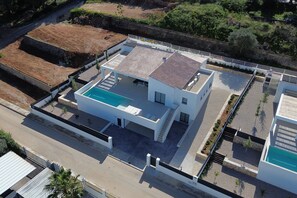 A modern two-story house with a rooftop pool, a paved driveway, and a landscaped garden. - 0143 Villa Cap Cabanes (Javea)
