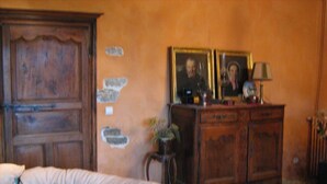 A room with a bed, a wooden dresser, and a wall with a decorative plaster design. - Guest Room “La Jonquille” with Private Garden and Wi-Fi (Foissy)