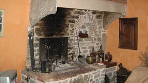 A stone fireplace with a brick arch, a wooden door, and various historical objects. - Guest Room “La Jonquille” with Private Garden and Wi-Fi (Foissy)