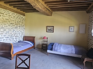 A room with two wooden beds, a stone wall, and a simple chair. - Guest Room “L’Iris” with Private Garden and Wi-Fi (Foissy)