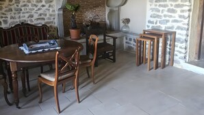 A rustic dining area with a brick fireplace, wooden furniture, and a stone wall.