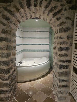 A bathroom with a stone archway, a bathtub, and tiled walls.