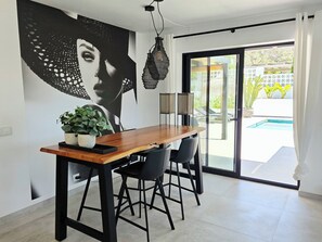 A dining area with a wooden table, black chairs, a potted plant, and a large wall mural.
