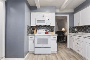 Une cuisine moderne avec des meubles blancs, un four à micro-ondes, une cuisinière et un coin repas comprenant une table et des chaises.