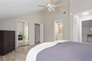 Une chambre à coucher comprenant un lit, une commode, un placard et un ventilateur de plafond.