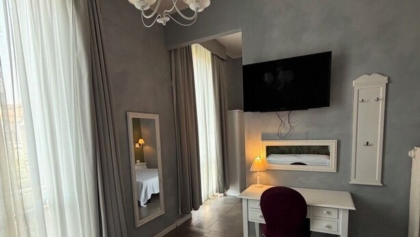Een hotelkamer met een bed, een bureau, een stoel, een televisie en een spiegel.