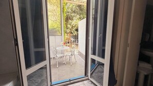 Een schuifdeur die leidt naar een terras met een tafel en stoelen.