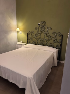 A bedroom with a metal headboard, a bedside table, and a lamp. - Boutique Hotel Washington Milano (Milan)