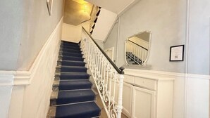 Een trap met witte spijlen en tredes met blauw tapijt.