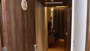 A hallway with wooden flooring, a door with a number plate, and a ceiling with recessed lighting. - The Cedar Grand Hotel And Spa (Shimla)