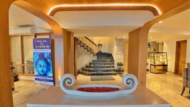A hotel lobby with a marble reception desk, a staircase with a black and white marble design, and a poster advertising a spa. - The Cedar Grand Hotel And Spa (Shimla)