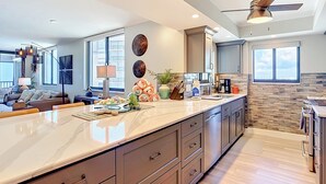 Una cucina moderna con un'isola grande, elettrodomestici integrati e una ventola a soffitto.