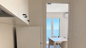 Una cocina moderna con armarios blancos, encimera negra y vistas a un comedor con sillas y una mesa.