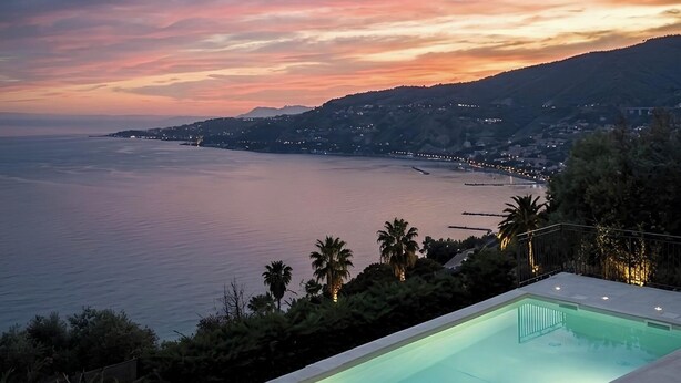 Una piscina con vista al mar y al atardecer.