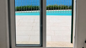 Puerta que da a un balcón con piscina y vista al océano.