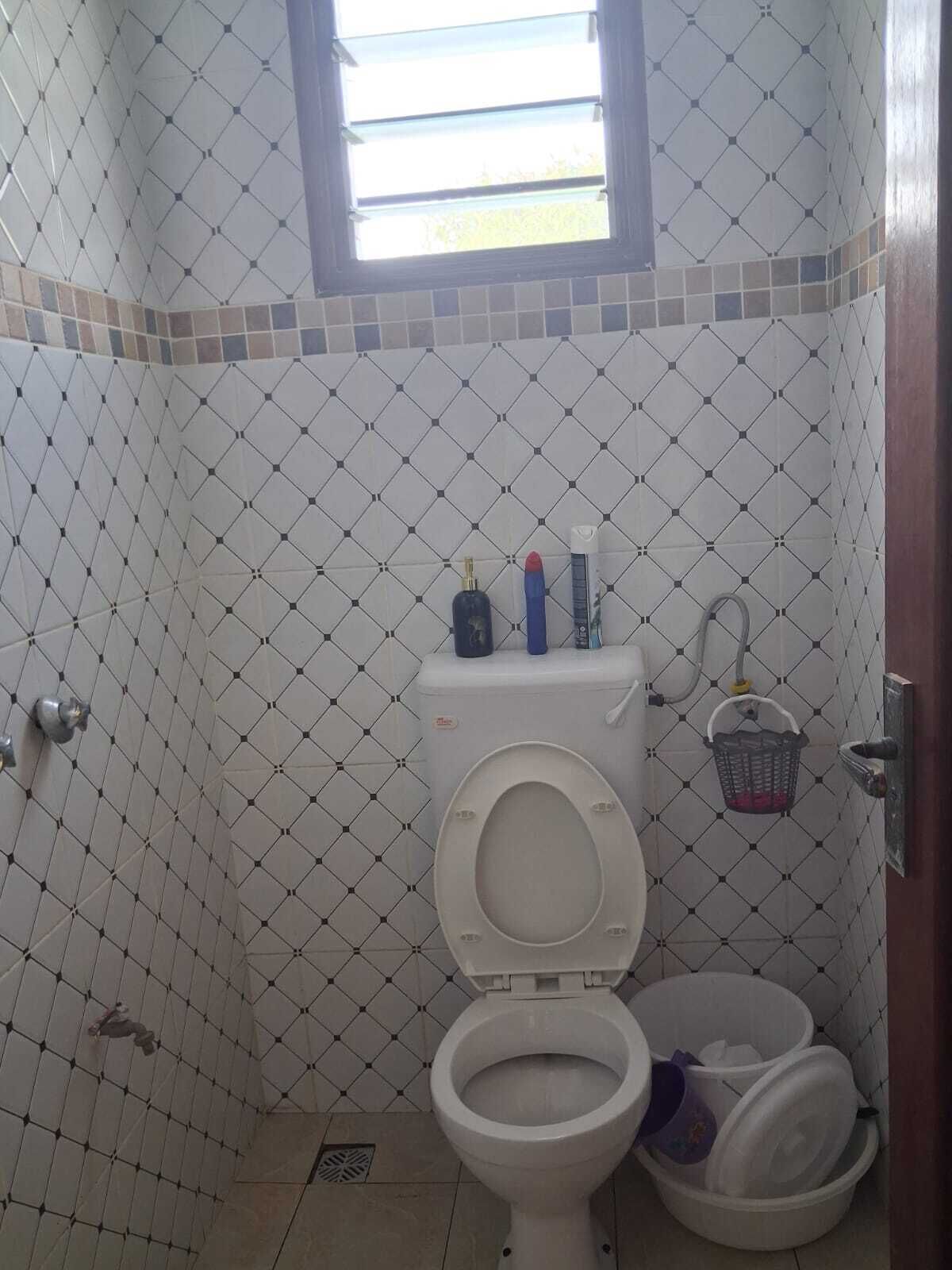 Un baño con inodoro, bidé, ventana y pared con azulejos.