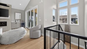 Een moderne keuken met een ingebouwde oven, een eethoek met een witte tafel en stoelen, en een trap die leidt naar een verdieping.