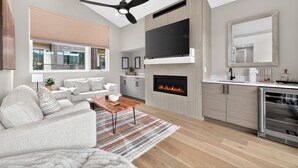 Een moderne woonkamer met een open haard, een flatscreen televisie en een eethoek.