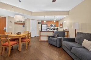 A compact living space with a dining area, kitchenette, and a gray sofa.